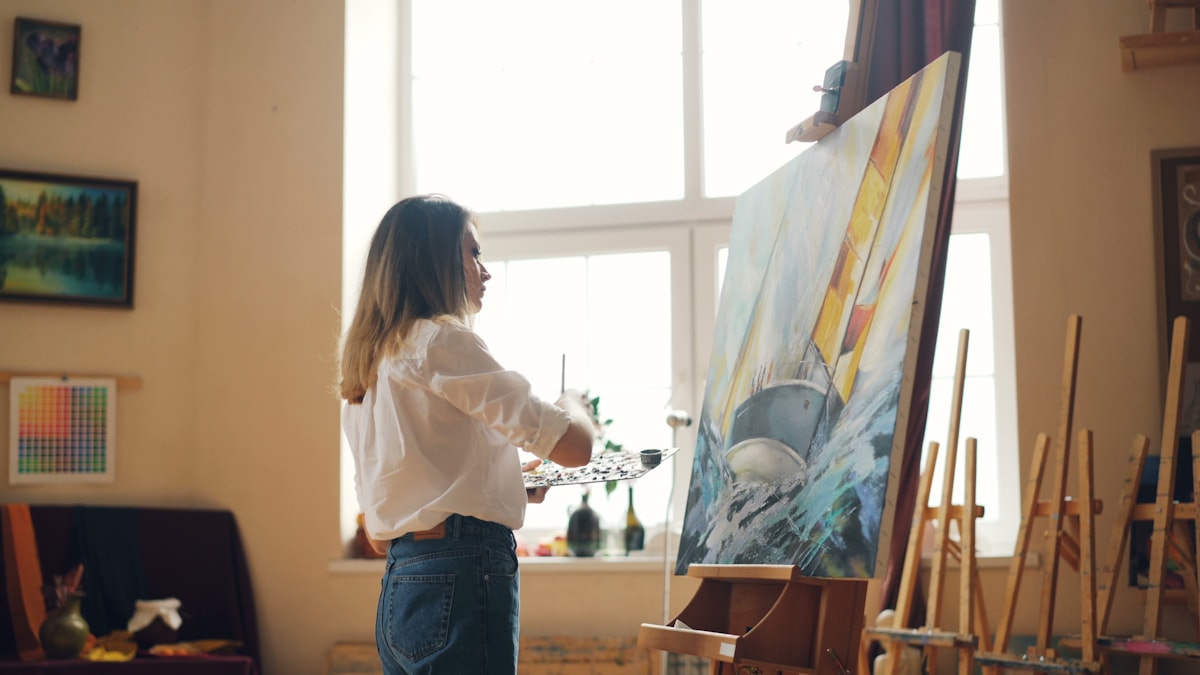 Artist painting on a large canvas in a bright studio